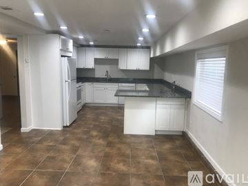 Galveston apartment for rent - A kitchen with white cabinets and brown tiled floors.