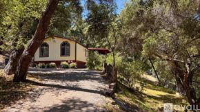 Topanga apartment for rent - A small house with a red roof is surrounded by trees and greenery.