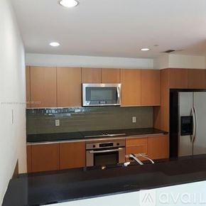 Miami apartment for rent - A kitchen with wooden cabinets and a black countertop.