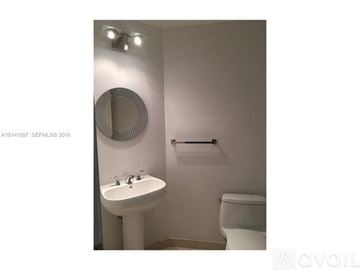 Miami apartment for rent - A large, modern living room with a long white couch and a chandelier hanging from the ceiling.