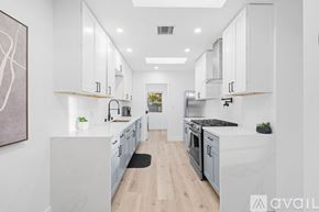 San Diego house for rent - A modern kitchen with white cabinets and a wooden floor.