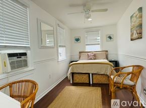 Milford apartment for rent - A bedroom with a bed, chair, and window with blinds.