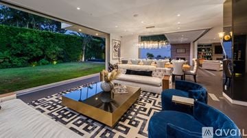 Beverly Hills house for rent - A modern living room with a large coffee table and blue chairs.