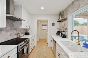 Plano house for rent - A kitchen with white cabinets and black countertops.