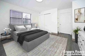 Boston apartment for rent - A bedroom with a large bed and a small nightstand with a vase of flowers on it.