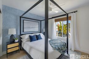 Huntington Beach house for rent - A bedroom with a four poster bed and a window with a view of the outside.