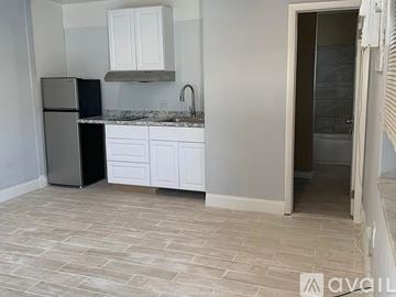 Hollywood house for rent - A kitchen with a black fridge, white cabinets, and a marble countertop.