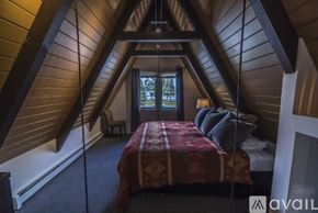 Truckee house for rent - A bedroom with a bed in the middle of the room with a window behind it.
