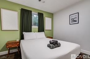 Houston house for rent - A bedroom with a white bed and a green wall.