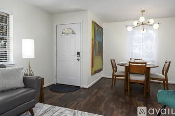 Vestavia Hills condo for rent - A living room with a grey couch, a wooden dining table and chairs, and a painting on the wall.