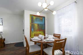 Vestavia Hills condo for rent - A dining room with a wooden table and chairs, a painting on the wall, and a window with white curtains.