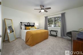 Vestavia Hills condo for rent - A bedroom with a bed covered in an orange sheet, a ceiling fan, and a window with a view of trees outside.
