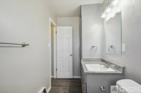 Colorado Springs apartment for rent - A bathroom with a sink, mirror, toilet, and a door.