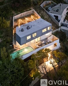 West Hollywood apartment for rent - A modern house with a pool at night.