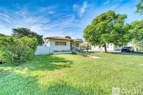 Miami house for rent - A house with a white fence and a tree in front of it.