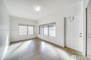 Miami house for rent - A white room with a door and two windows.