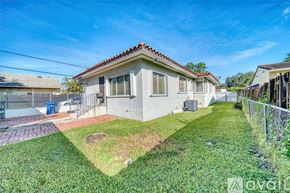 Miami house for rent - A small house with a red tile roof and a fenced yard.