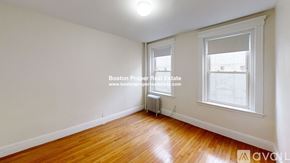 Boston apartment for rent - A room with wooden floors and white walls, with a window and a radiator.