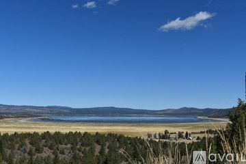 Susanville house for rent - A vast landscape with a lake, sandy beach, and mountains in the distance under a clear blue sky.