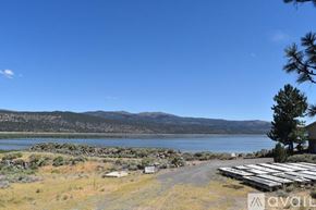 Susanville house for rent - A lake with a house and a tree in the foreground.