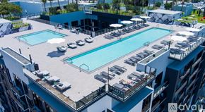 Miami apartment for rent - A rooftop pool area with lounge chairs and a building in the background.
