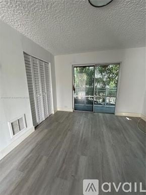 Miami apartment for rent - A room with a grey floor and a sliding glass door.