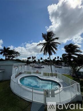 Miami apartment for rent - A pool surrounded by a white fence with palm trees in the background.