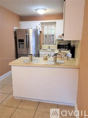 Miami apartment for rent - A kitchen with a refrigerator, microwave, and sink.