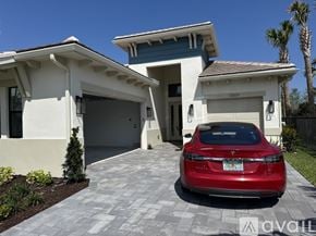 Palm Beach Gardens house for rent - A red car is parked in front of a two-story house.
