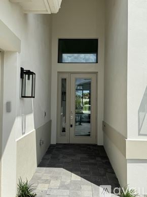 Palm Beach Gardens house for rent - A modern house entrance with a glass door and a black lantern on the wall.