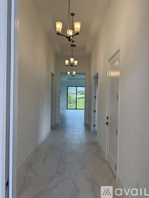 Palm Beach Gardens house for rent - A long hallway with a chandelier and doors on both sides.