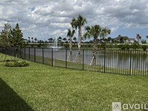 Palm Beach Gardens house for rent - A grassy area with a fence and trees in front of a body of water.