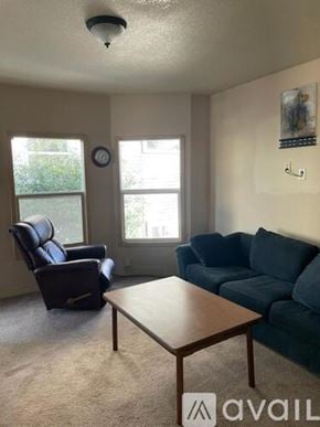Portland apartment for rent - A living room with a blue couch, a brown coffee table, and a window.