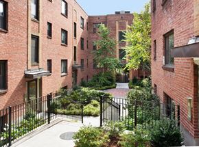 Brookline apartment for rent - a courtyard between two red brick buildings with trees and bushes