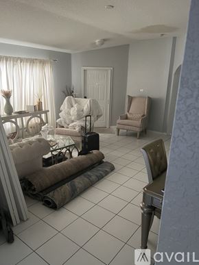 Miramar apartment for rent - A room with a white sofa, a chair, and a table with a vase on it.