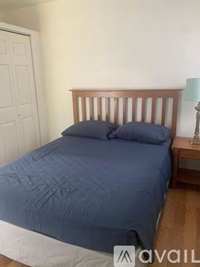 Miramar apartment for rent - A bed with a blue comforter and two pillows sits in a room with a wooden headboard.