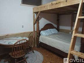 Elkhart apartment for rent - A wooden bunk bed with a ladder is in a room with a table and chair.