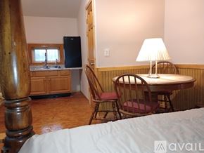 Elkhart apartment for rent - A bedroom with a bed, a table with chairs, and a kitchen area with a refrigerator and sink.