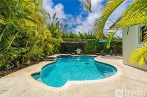 Miami house for rent - A heart-shaped pool surrounded by palm trees and a house.