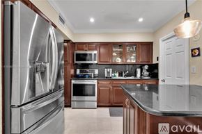Miami house for rent - A kitchen with a stainless steel refrigerator and wooden cabinets.