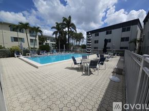 Naples condo for rent - A pool surrounded by chairs and palm trees.