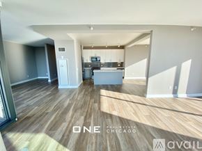 Chicago apartment for rent - A spacious living room with wood flooring and a kitchen area in the background.