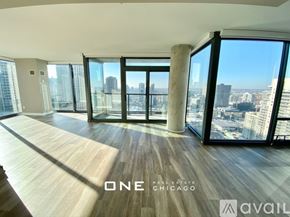 Chicago apartment for rent - A spacious room with wooden floors and large windows overlooking a cityscape.
