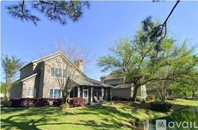 Gulf Shores apartment for rent - A house with a well-maintained lawn and trees in the background.