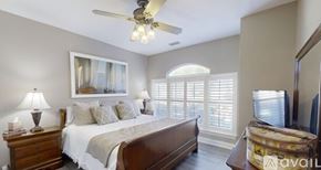Gulf Shores apartment for rent - A bedroom with a large bed, a ceiling fan, and a painting on the wall.