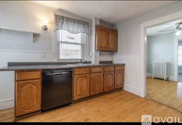 Bangor apartment for rent - A kitchen with wooden cabinets and a black dishwasher.