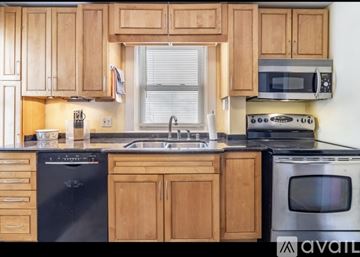 Bangor apartment for rent - A kitchen with wooden cabinets and black appliances.