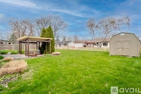 Lafayette house for rent - A grassy field with a wooden shelter and a large metal shed.