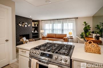 Lafayette house for rent - A modern kitchen with a stove top oven and a living room area with a couch and a plant.