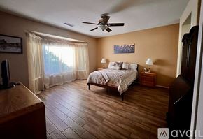 Surprise house for rent - A bedroom with a bed, a ceiling fan, and a window with curtains.
